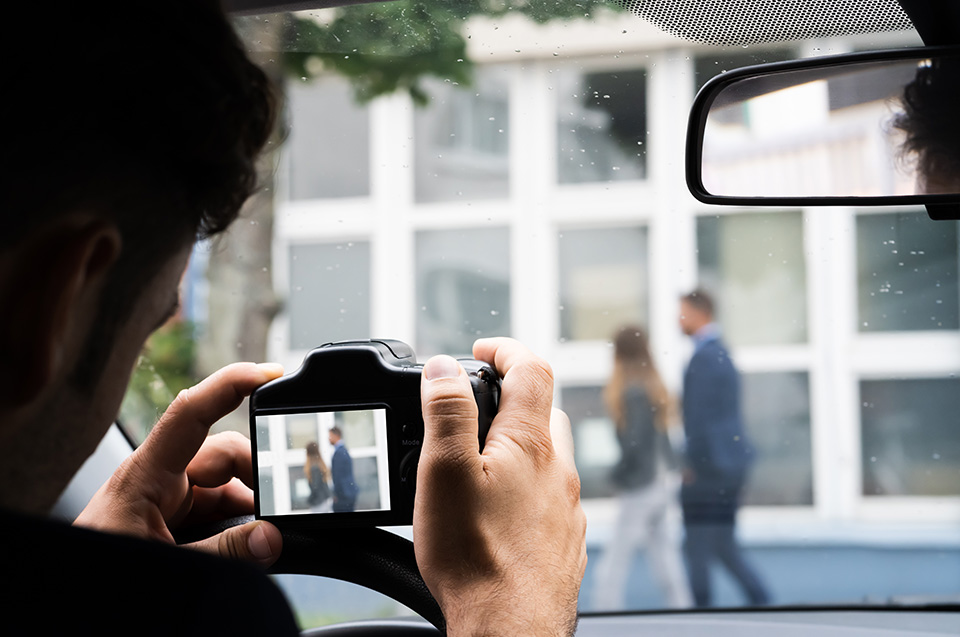 Un detective fotografiando a una pareja desde su coche.